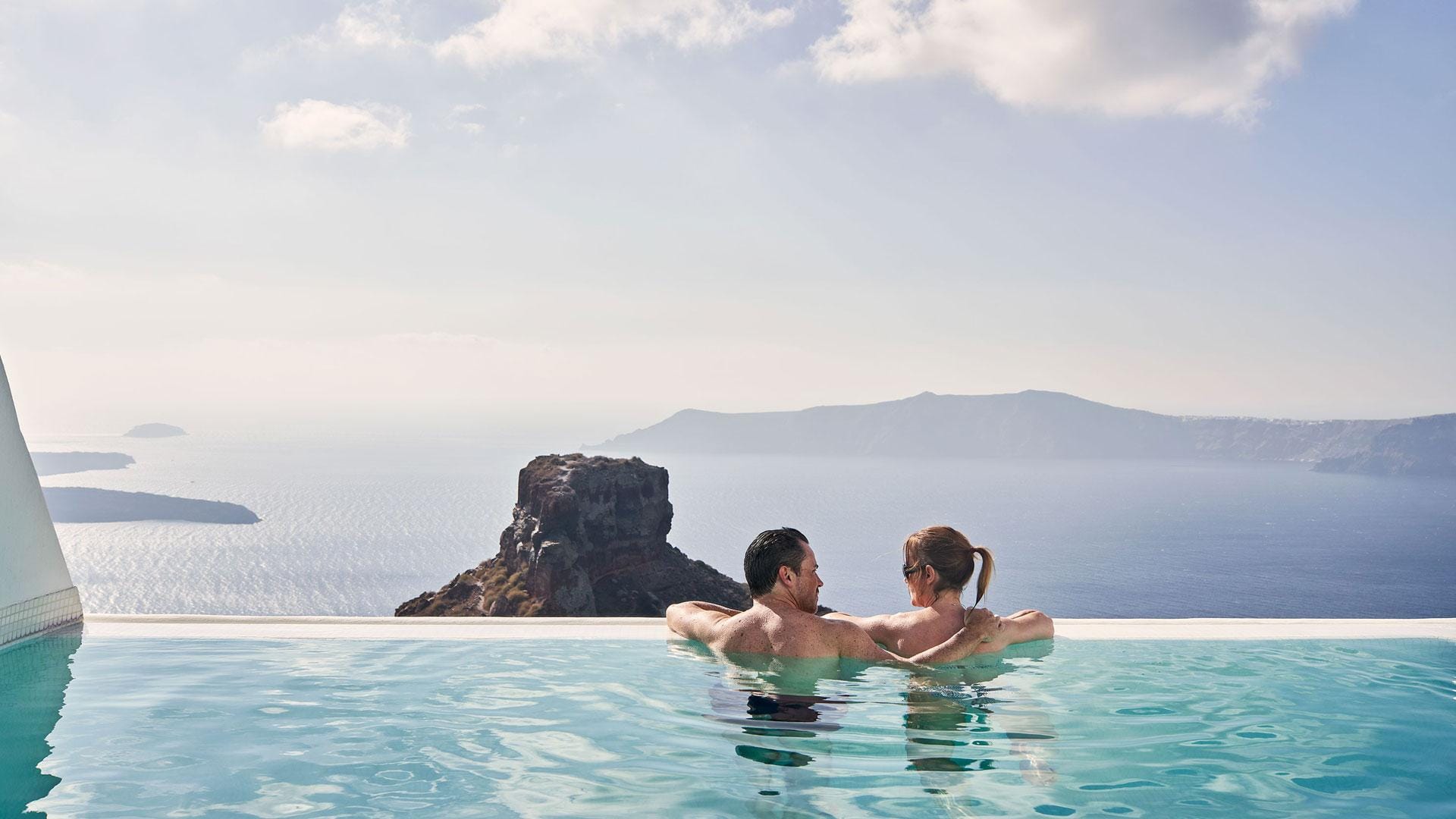 casal em lua de mel numa praia ao pôr do sol boutique hotel elegante em santorini