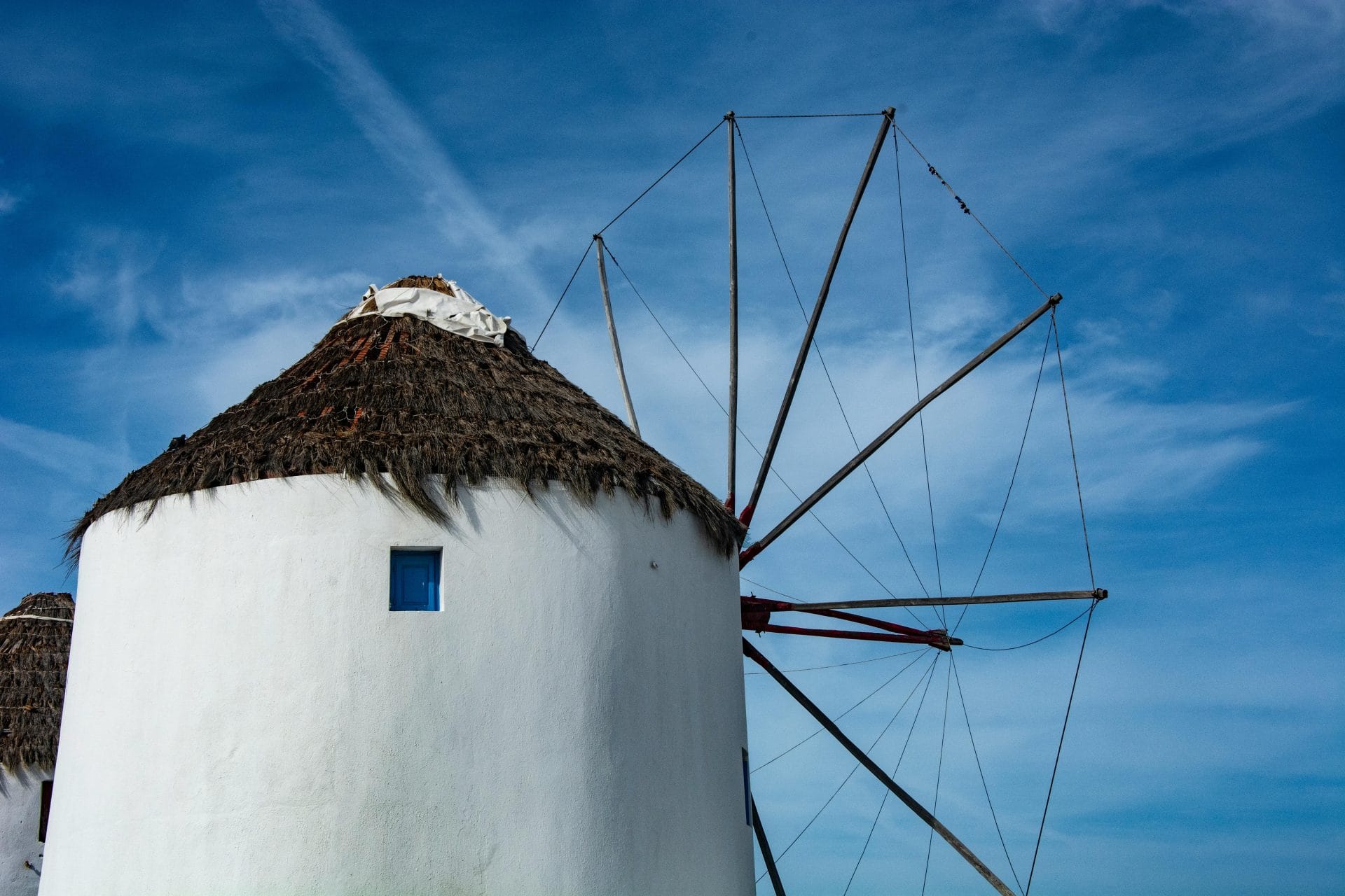 Beautiful view of a traditional windmill in Mykonos, Greece against a blue sky.